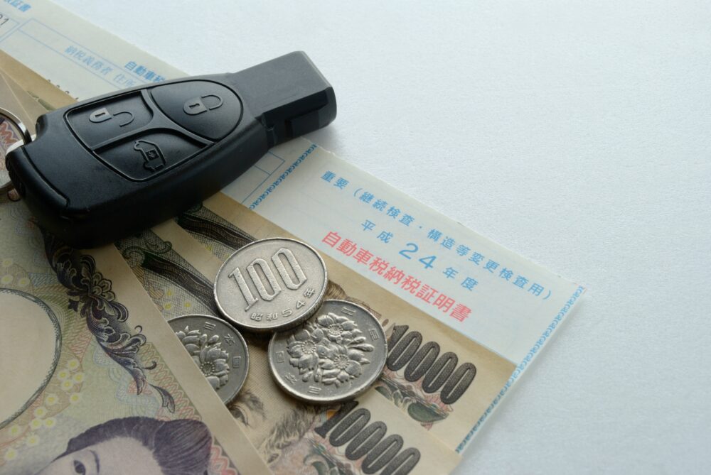 納税証明書の上に置かれた車の鍵とお金